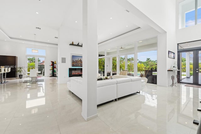 living room featuring a high ceiling, plenty of natural light, and french doors