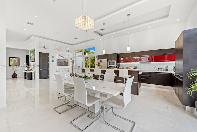 dining area featuring a towering ceiling and a raised ceiling