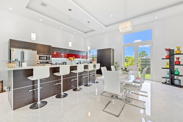 kitchen with stainless steel appliances, a high ceiling, a kitchen breakfast bar, pendant lighting, and french doors