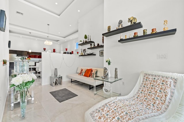 living area featuring a tray ceiling, light tile patterned floors, and a towering ceiling