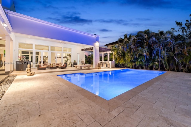 pool at dusk featuring a patio area