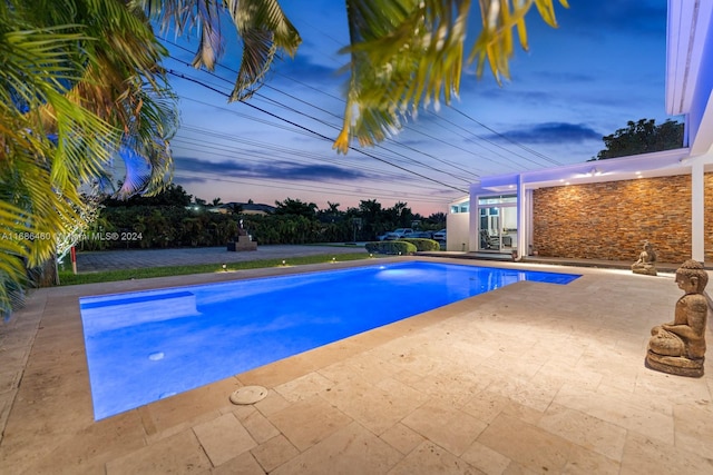 pool at dusk with a patio area