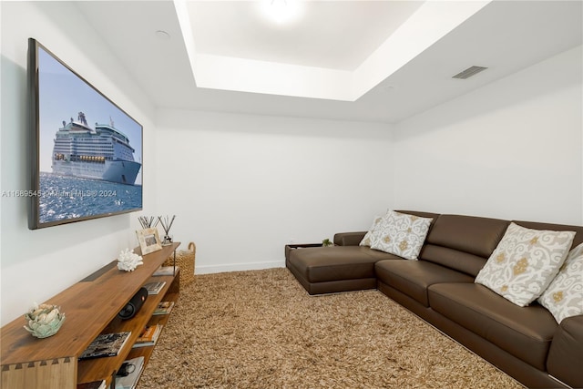 living room with a tray ceiling and carpet floors