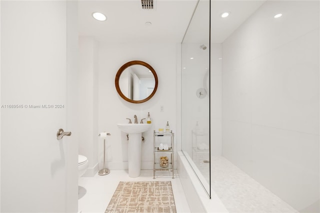 bathroom featuring toilet, tiled shower, and tile patterned floors