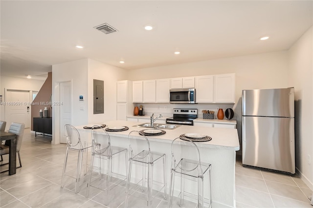 kitchen with stainless steel appliances, white cabinetry, sink, a breakfast bar area, and an island with sink