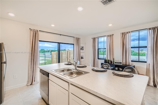 kitchen featuring stainless steel appliances, a center island with sink, sink, light tile patterned flooring, and white cabinetry