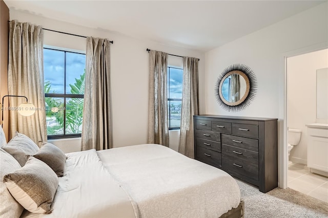 bedroom with light tile patterned flooring, multiple windows, and connected bathroom