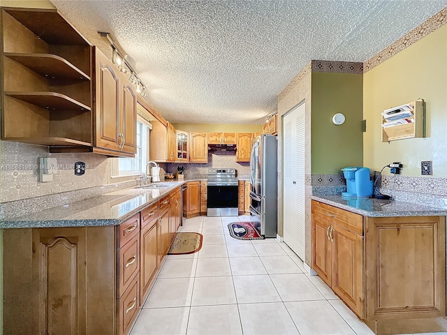 kitchen with stainless steel appliances, light tile patterned flooring, sink, light stone counters, and a textured ceiling