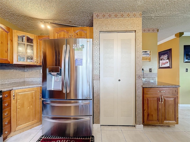 kitchen featuring a textured ceiling, light tile patterned floors, stainless steel fridge, and crown molding