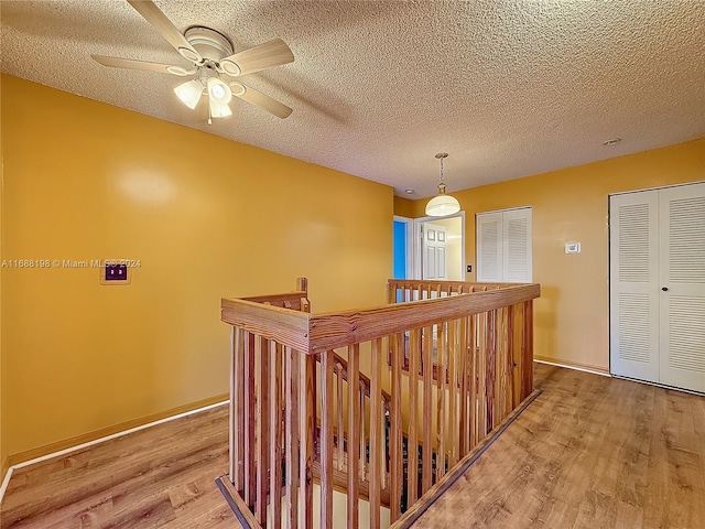 corridor with a textured ceiling and hardwood / wood-style flooring