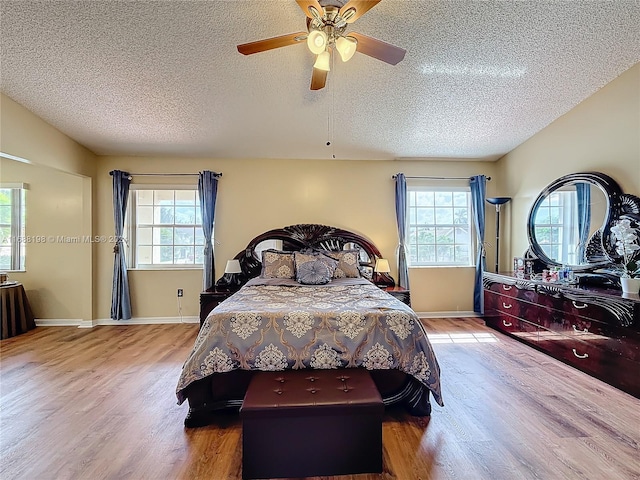 bedroom featuring ceiling fan, multiple windows, and light wood-type flooring