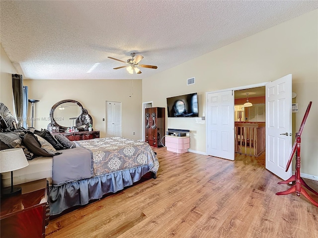 bedroom featuring hardwood / wood-style floors, ceiling fan, a textured ceiling, and lofted ceiling