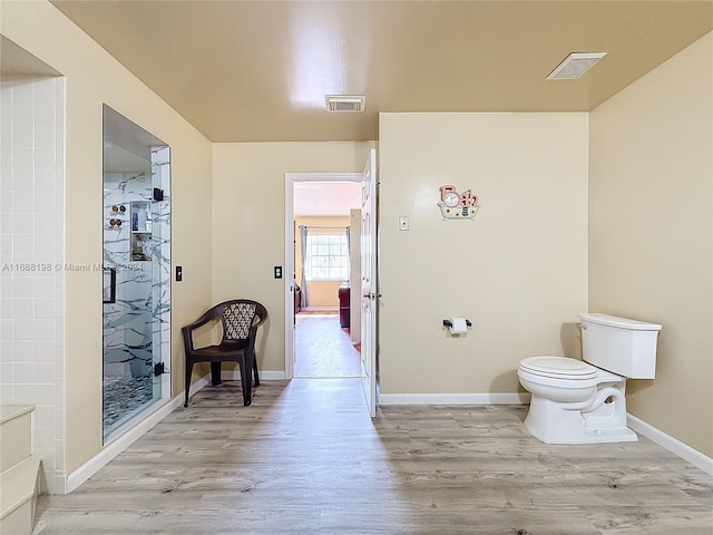 bathroom featuring toilet, hardwood / wood-style flooring, and a shower with shower door