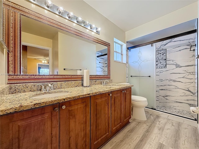 bathroom featuring hardwood / wood-style floors, tiled shower, toilet, and vanity