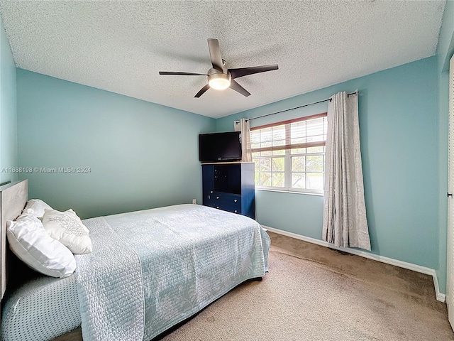 bedroom with a textured ceiling, carpet flooring, and ceiling fan