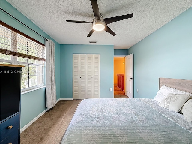 carpeted bedroom with a textured ceiling, ceiling fan, and a closet