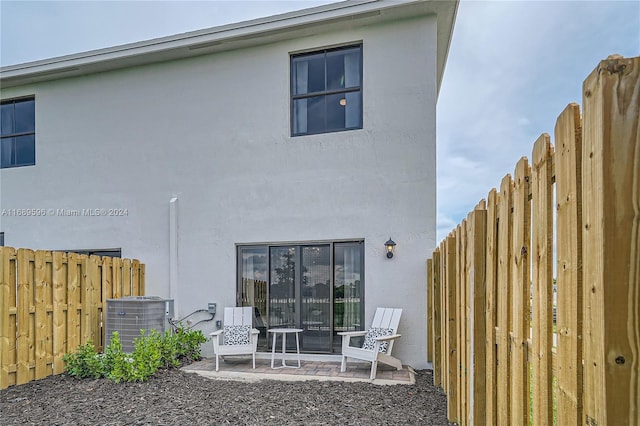 back of property with central AC and a patio