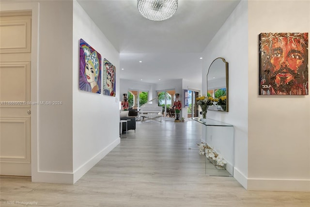 hall with light hardwood / wood-style flooring and a notable chandelier