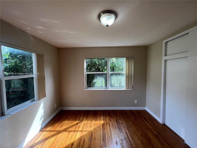 unfurnished bedroom featuring wood-type flooring, a textured ceiling, and a closet