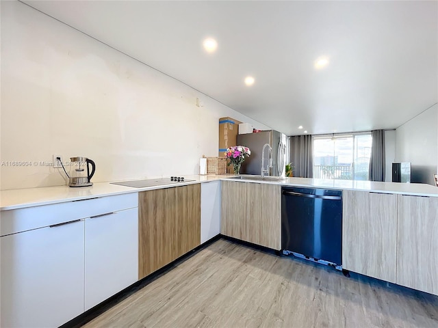 kitchen with light hardwood / wood-style floors, sink, black appliances, kitchen peninsula, and light brown cabinetry