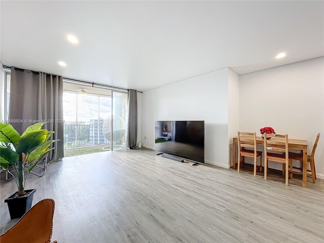 living room featuring a wall of windows and light hardwood / wood-style flooring