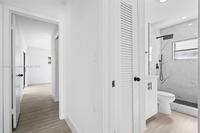 bathroom featuring tiled shower, toilet, and hardwood / wood-style flooring