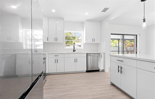 kitchen featuring decorative light fixtures, stainless steel appliances, backsplash, white cabinetry, and sink