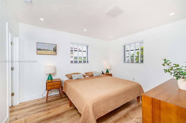 bedroom with light hardwood / wood-style floors and multiple windows