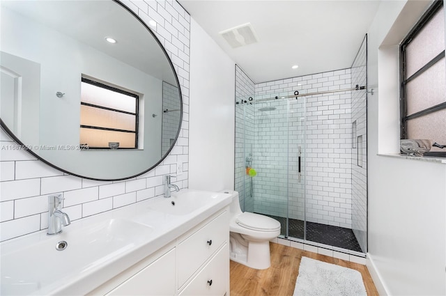 bathroom with toilet, hardwood / wood-style flooring, vanity, backsplash, and a shower with shower door