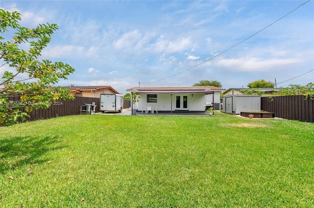 rear view of house featuring a storage unit, a lawn, and a patio area