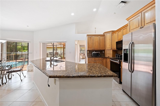 kitchen with stainless steel appliances, backsplash, sink, an island with sink, and lofted ceiling