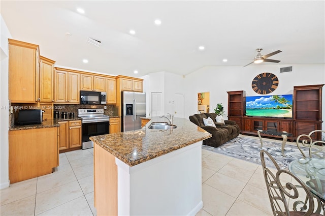 kitchen with a center island with sink, appliances with stainless steel finishes, light tile patterned floors, sink, and vaulted ceiling