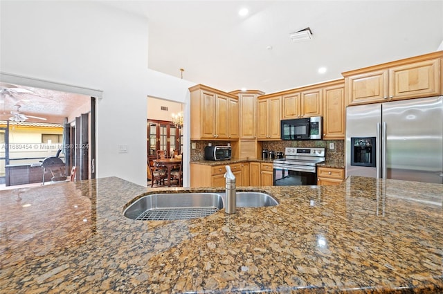 kitchen featuring appliances with stainless steel finishes, sink, light brown cabinetry, and dark stone countertops