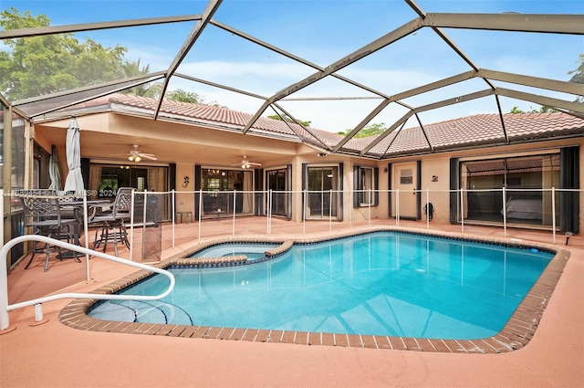 view of swimming pool with a patio area, ceiling fan, glass enclosure, and an in ground hot tub