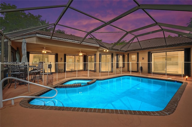 pool at dusk with ceiling fan, a lanai, an in ground hot tub, and a patio area