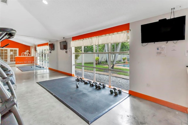 gym with concrete flooring, a textured ceiling, and lofted ceiling