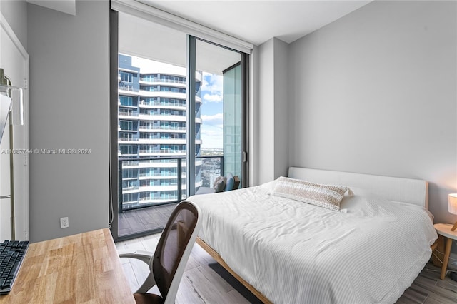 bedroom with hardwood / wood-style floors, expansive windows, and access to outside