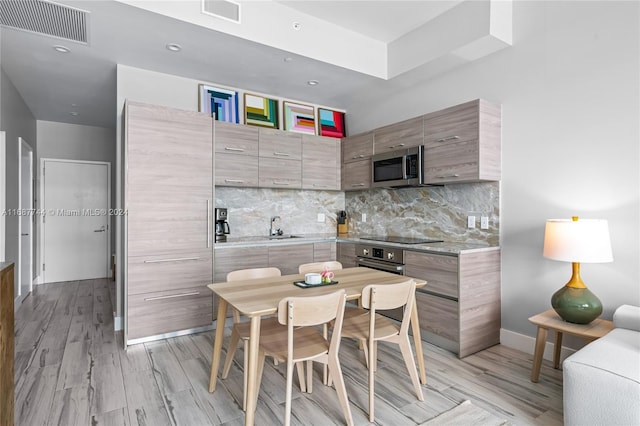 kitchen with light hardwood / wood-style floors, sink, backsplash, and appliances with stainless steel finishes