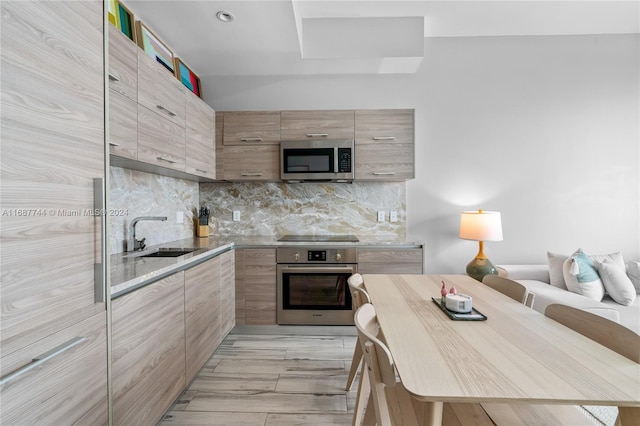 kitchen featuring stainless steel appliances, light brown cabinetry, sink, and decorative backsplash