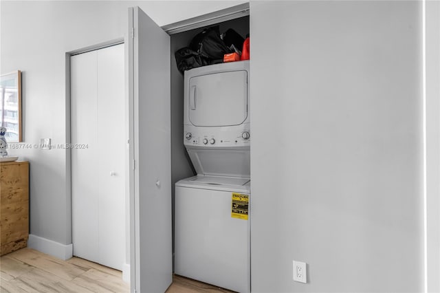 washroom with stacked washer and clothes dryer and light wood-type flooring