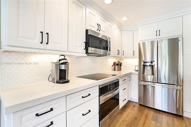 kitchen featuring stainless steel appliances, light stone counters, light hardwood / wood-style flooring, white cabinets, and decorative backsplash