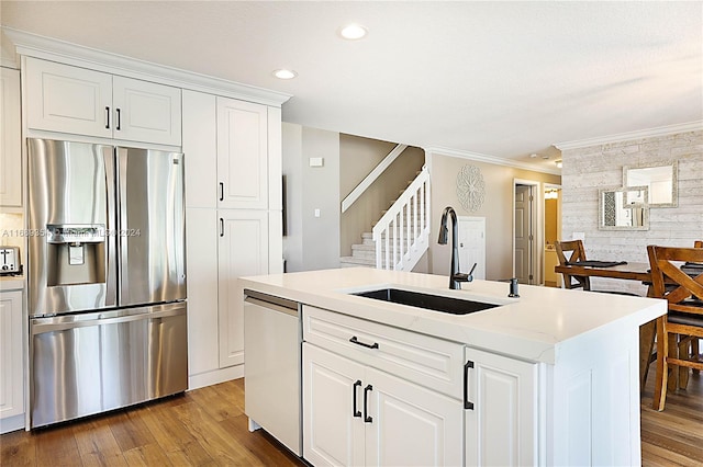 kitchen featuring white cabinetry, stainless steel fridge with ice dispenser, sink, dishwasher, and a kitchen island with sink