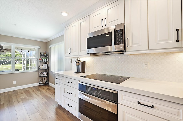 kitchen featuring stainless steel appliances, crown molding, backsplash, white cabinetry, and light hardwood / wood-style flooring