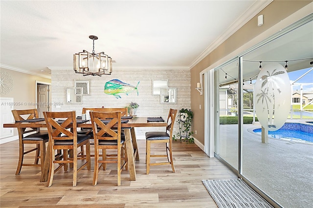 dining area with light wood-type flooring, an inviting chandelier, and ornamental molding