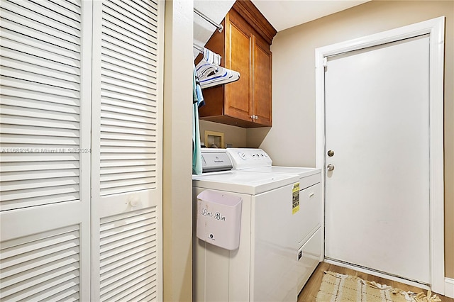 clothes washing area with light hardwood / wood-style floors, washing machine and dryer, and cabinets