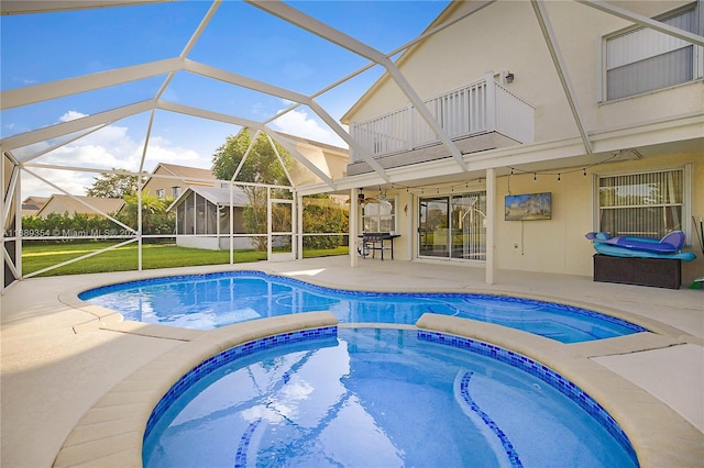 view of swimming pool featuring glass enclosure, a lawn, a patio, and an in ground hot tub