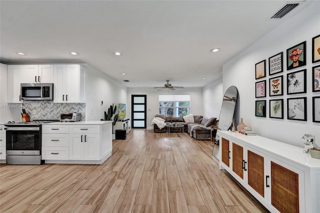 kitchen featuring stainless steel appliances, ceiling fan, white cabinets, and light hardwood / wood-style flooring