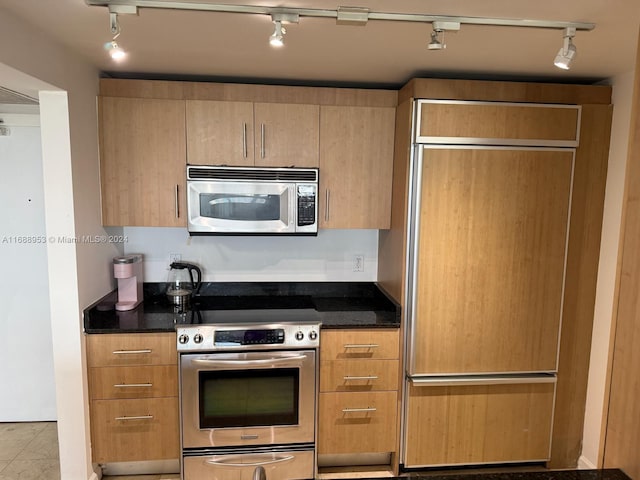 kitchen featuring track lighting, appliances with stainless steel finishes, and dark stone counters