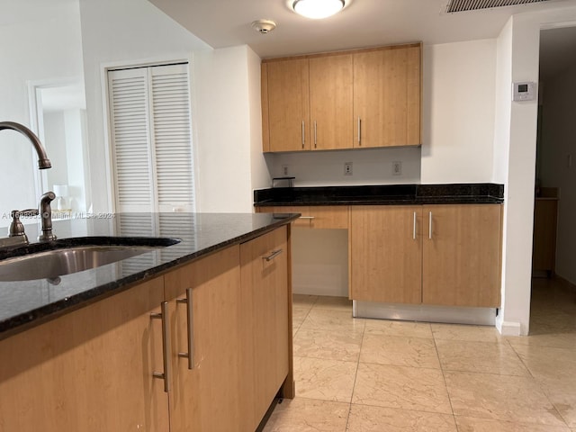 kitchen featuring dark stone counters and sink