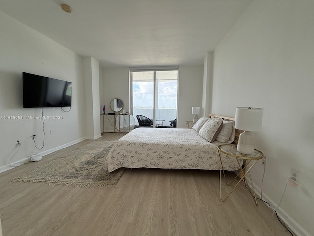 bedroom featuring light wood-type flooring and a wall of windows